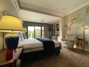 een slaapkamer met een groot bed en een stoel bij The Ridgeback, 4 Bedroom Good Living, Bryanston in Johannesburg +32 foto's