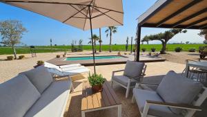 a patio with chairs and an umbrella and a pool at Masos Bruguera - Finca Llambrich in Deltebre