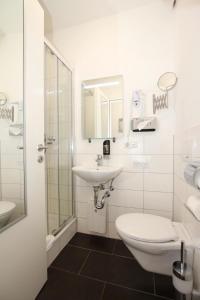 a white bathroom with a sink and a toilet at Apartment Hotel am Sand 24H Self Check-in in Hamburg