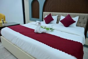 a white cat laying on a red blanket on a bed at Hotel Akshay in Jaipur