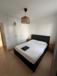 a bedroom with a white bed with a black headboard at Casa Oasis in Corralejo