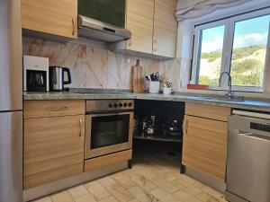 een keuken met houten kasten en een kookplaat met oven bij Panorama SeaView House in Marinha Grande +30 foto's