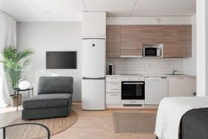 a white kitchen with a chair and a refrigerator at Stylish, 450 m walk to the Estonian ferry, Free parking and balcony in Helsinki