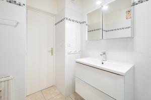 a white bathroom with a sink and mirror at meublé tourisme 3 étoiles vue mer in Golfe-Juan +14 photos