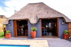 ein blaues Haus mit Strohdach und einem Pool in der Unterkunft The Hemingway House 14 Resort Pool in Benoni