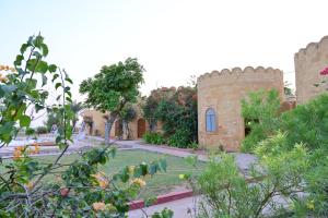 Un edificio de ladrillo con un jardín delante. en Himmatgarh Palace Heritage Boutique Hotel, en Jaisalmer