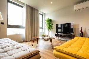 a living room with a yellow couch and a tv at Extra Large 2BR Apartment Next to Metro Station in Bicas