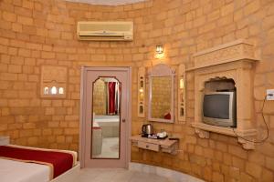 Una habitación de hotel con televisión y un dormitorio. en Himmatgarh Palace Heritage Boutique Hotel, en Jaisalmer