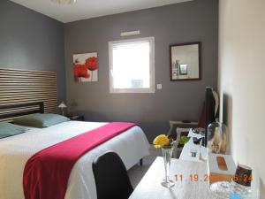 a bedroom with a bed and a desk and a window at Les Coquelicots Chambre d' hote avec grand lit et salle d'eau privative pour une persone ou un couple in Vern-sur-Seiche