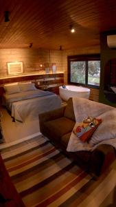 ein Schlafzimmer mit zwei Betten und einer Couch und einer Badewanne in der Unterkunft L'esperienza - Chalés completos - Ecoturismo in Nova Petrópolis
