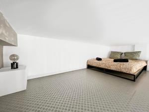 a bedroom with a bed in a white wall at Loft cosy, Canapé-lit & Mezzanine, cœur de Cambrai in Cambrai