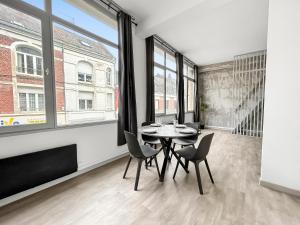 a dining room with a table and chairs and windows at Loft cosy, Canapé-lit & Mezzanine, cœur de Cambrai in Cambrai