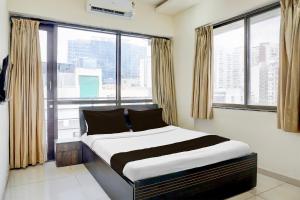 a bedroom with a large bed in front of windows at Hotel O Destination 41 in Pune