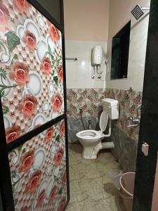ein Bad mit einem WC und einer Blumenwand in der Unterkunft The Village Retreat in Alībāg