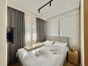 um quarto com uma cama branca com duas toalhas brancas em Zlatibor Prestige Apartman 18 em Zlatibor