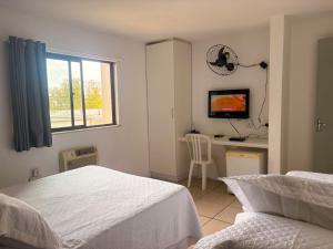 a bedroom with a bed and a desk with a television at Stratus Centro Hotel in Volta Redonda