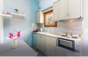 a kitchen with white cabinets and a vase of flowers at Loukia's apartment no 2 in Mesochórion +8 photos