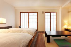 2 camas y una mesa en una habitación con ventanas en Yukkura Inn en Aizuwakamatsu