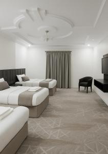 a hotel room with two beds and a flat screen tv at فندق التاج ثلاثة مكة in Mecca