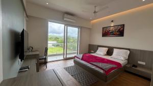 a bedroom with a bed and a large window at Sairaj Lawns in Belgaum