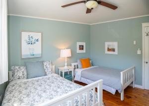 a bedroom with two beds and a ceiling fan at Summer By The Sea Beach House in Saint Peters