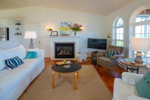 a living room with a white couch and a fireplace at Summer By The Sea Beach House in Saint Peters
