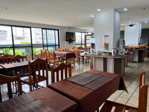 ein leeres Restaurant mit Tischen, Stühlen und Fenstern in der Unterkunft Stratus Centro Hotel in Volta Redonda