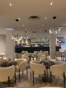 a restaurant with tables and chairs and a bar at Hôtel Alba in Lourdes