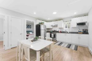 a kitchen with white cabinets and a white table and chairs at Lovely Coach House in Langley with Queen Beds Pkg in Langley