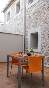 a dining room table with orange chairs in front of a brick wall at Cal Perot Apartamento turístico en Les Borges Blanques in Les Borges Blanques 