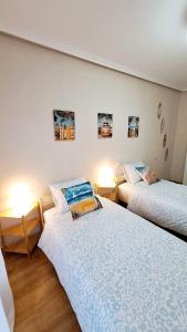 a bedroom with two beds and two lamps on the wall at Jona Candás Asturias in Candás