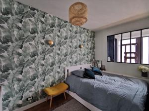 ein Schlafzimmer mit einem Bett und einem Wandbild in der Unterkunft Appartement rénové une chambre avec espace de travail in Suresnes
