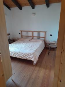ein Schlafzimmer mit einem Bett und einem Holzboden in der Unterkunft Ginepro Verde Apartment in Lorenzago