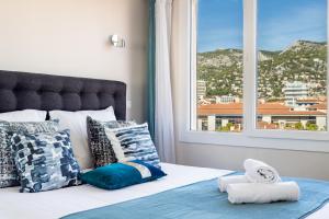 Un dormitorio con una cama con almohadas y una ventana. en Splendide appartement climatisé vue mer, en Toulon