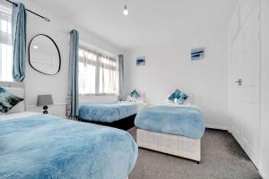 a bedroom with two beds and a mirror at Bella Homes-Spacious 4 bedroom Modern Town house Romford in Romford