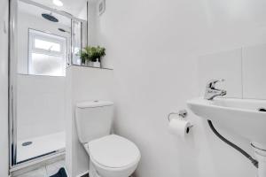 a white bathroom with a toilet and a sink at Bella Homes-Spacious 4 bedroom Modern Town house Romford in Romford +16 photos