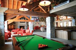 una sala biliardo con tavolo da biliardo e sedie rosse di Duplex confortable avec piscine a La Toussuire