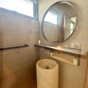La salle de bains est pourvue d'un miroir rond et de toilettes. dans l'établissement Verdana Cemagi Luxury Hostel, à Cemagi