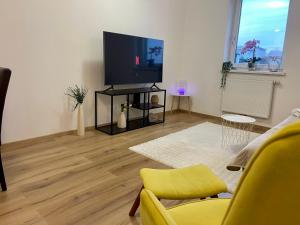 Una sala de estar con un televisor y una silla amarilla. en ModernLoft Ried, Balcony Suite, en Neuhofen im Innkreis