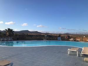 a swimming pool with chairs and mountains in the background at casa Maracujá in Majanicho