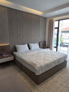 ein Schlafzimmer mit einem großen Bett und einem großen Fenster in der Unterkunft NEW Luxury 6BR Pool Villa Pattaya, 10mn Walking St in Jomtien Beach