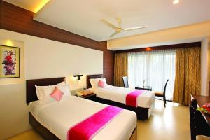 een hotelkamer met 2 bedden en een raam bij Holiday Vista Luxury Hotel and Spa, Thekkady in Thekkady