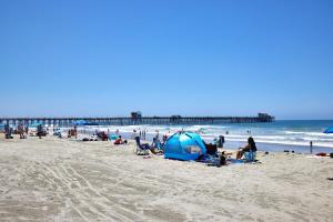 a group of people on a beach with a pier at 501P-12 Spectacular Ocean Views Pet Friendly in Oceanside