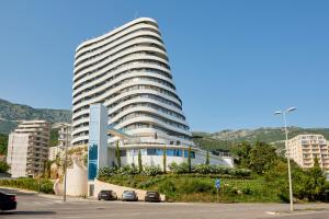 Un gran edificio blanco con coches aparcados delante. en Skyline resort CG, en Budva