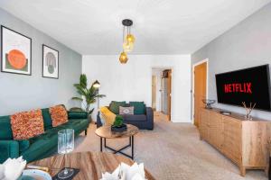 a living room with a green couch and a television at Queens Cove with Seaviews By My Getaways in Worthing