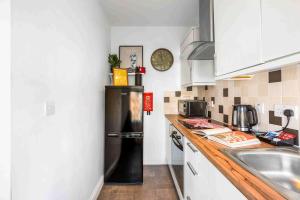a kitchen with a black refrigerator and a sink at Queens Cove with Seaviews By My Getaways in Worthing