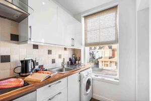a kitchen with a sink and a washing machine at Queens Cove with Seaviews By My Getaways in Worthing