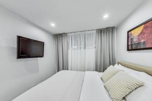 a white bedroom with a bed and a tv at Luxurious Lincoln Park Home with Gourmet Kitchen in Chicago