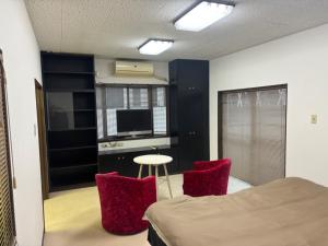 a bedroom with a bed and two red chairs at K5 Building - Vacation STAY 20273 in Nabegayato