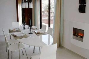 a white dining room table with white chairs and a fireplace at Casa Sevilla in Guía de Isora